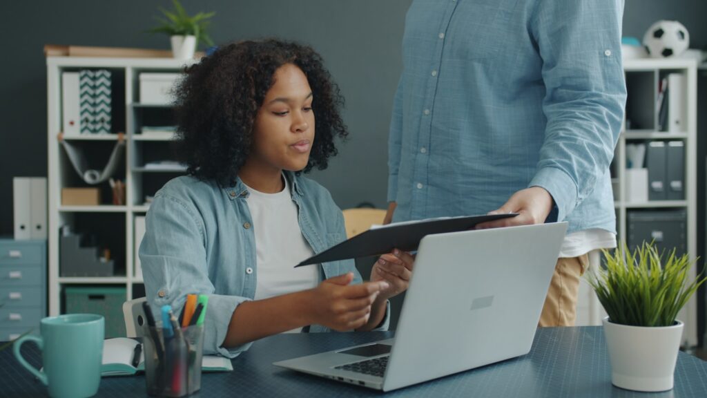 Two colleagues reviewing HR documents at an office desk